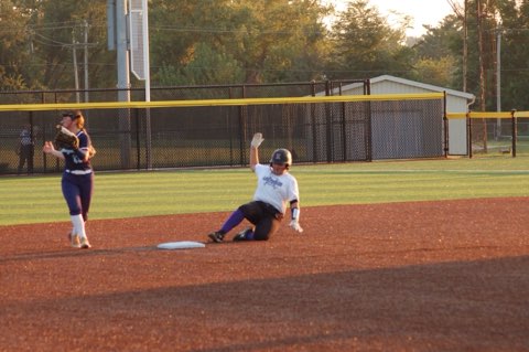 Ansley Turner is sliding into second  base  on the softball field because she does not want to get out by the catcher and she wants to be safe so that she can score.
