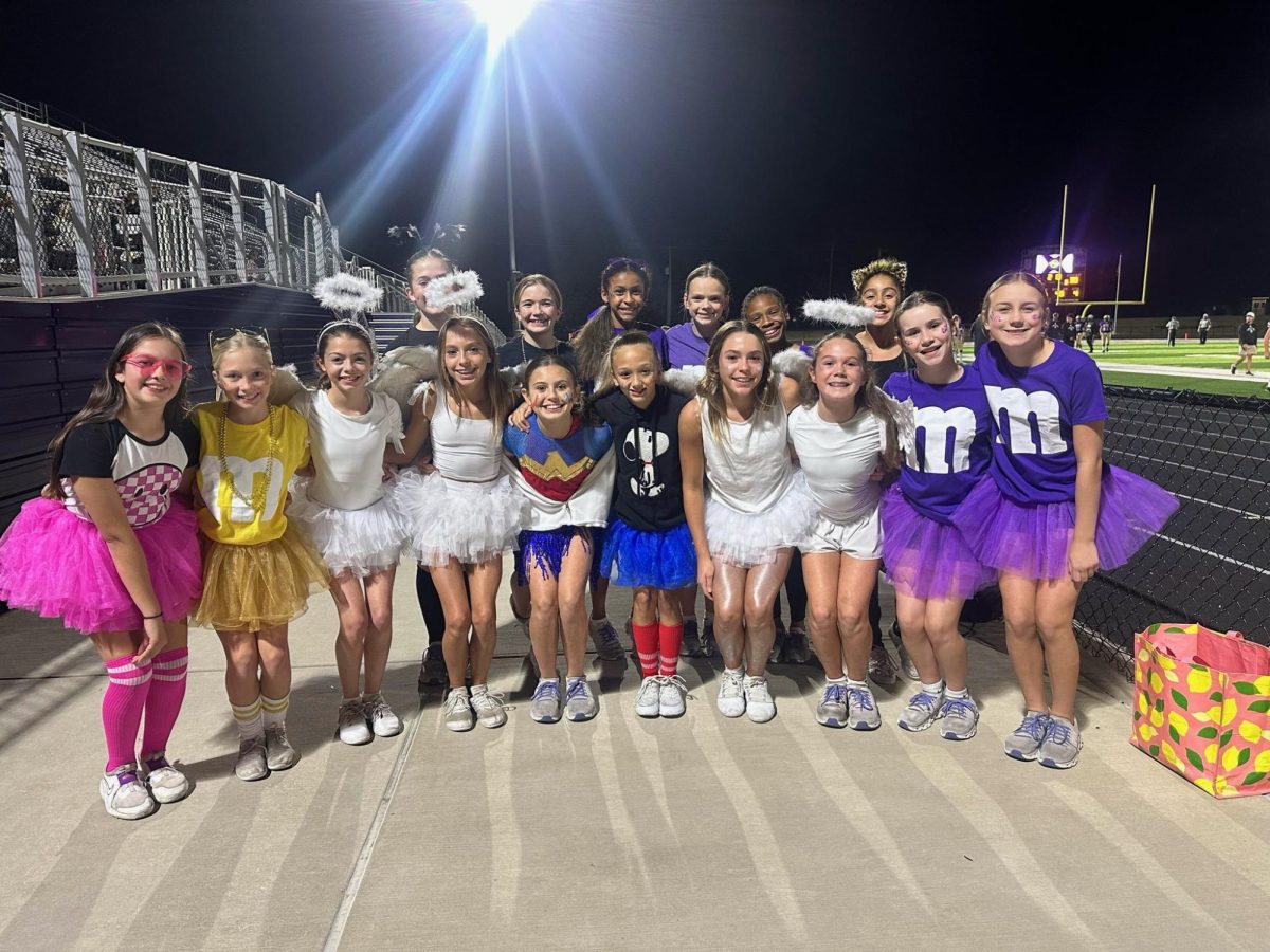 6th graders cheerleaders are enjoying spreading school spirit at the 8th-grade football game while dressing up for Halloween with their friends.